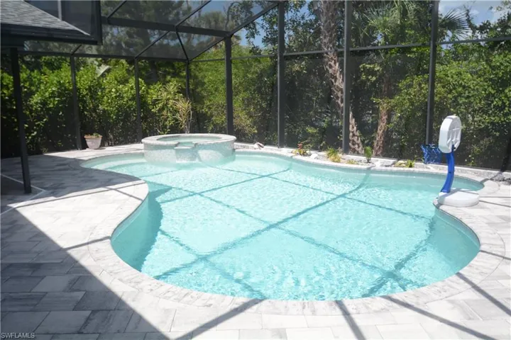View of swimming pool with a patio, a pool with connected hot tub, and glass enclosure