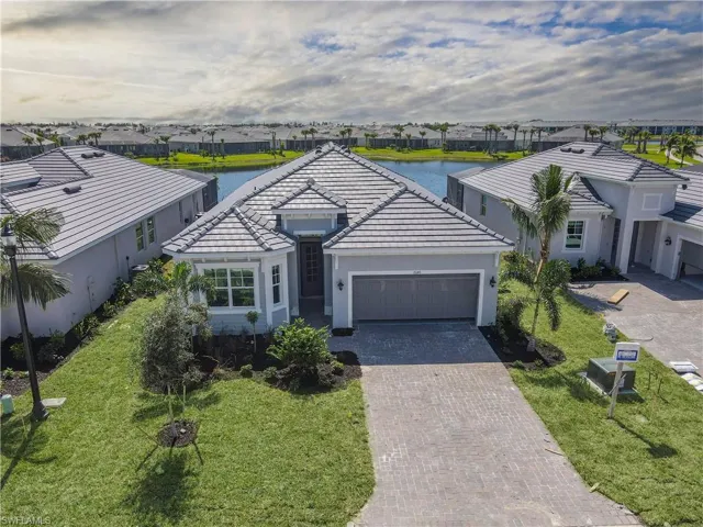 Ranch-style home with a garage, a water view, and a front lawn