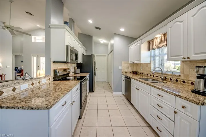 Beautifully updated Kitchen with Raised Panel Cabinetry, Granite tops, Tumbled Marble Backsplash + Stainless Steel Appliances