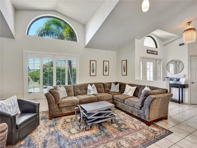 Sun drenched living room with arched window & plantation shutters