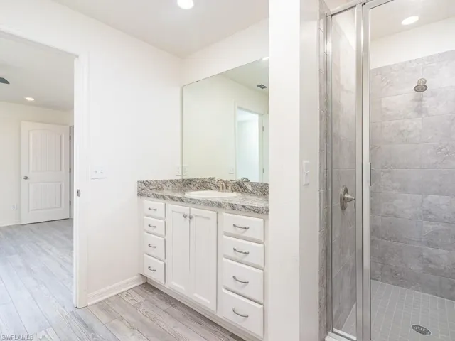 Bathroom featuring recessed lighting, light wood finished floors, a stall shower, and vanity