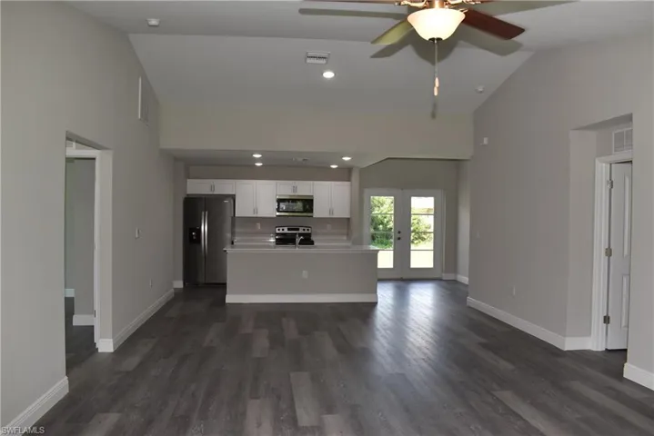 Unfurnished living room featuring high vaulted ceiling, ceiling fan, and dark hardwood / wood-style floors