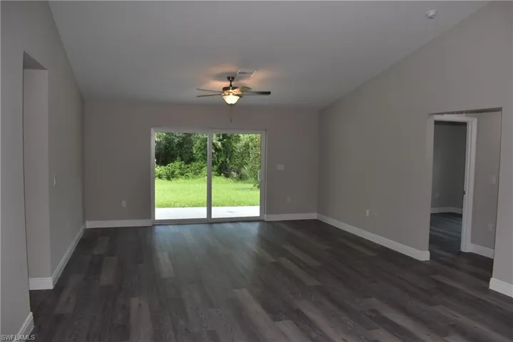 Empty room featuring ceiling fan, dark hardwood / wood-style flooring, and lofted ceiling