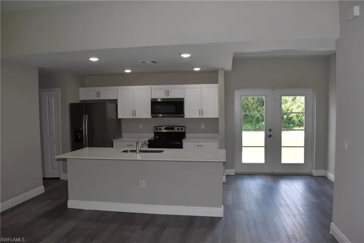 Kitchen featuring french doors, a center island with sink, dark hardwood / wood-style flooring, appliances with stainless steel finishes, and sink