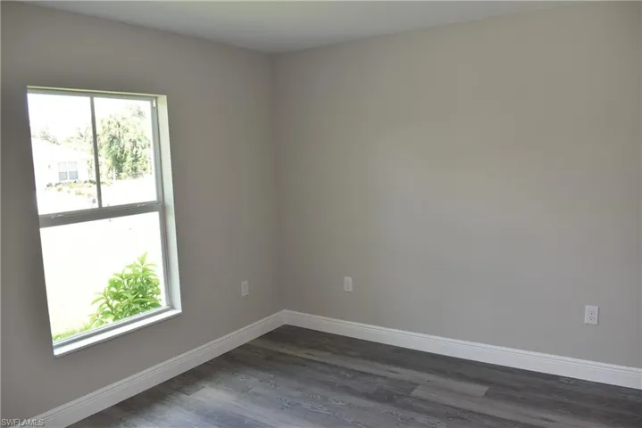 Empty room featuring dark wood-type flooring and a wealth of natural light