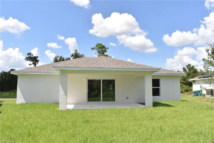 Back of house with a patio and a lawn