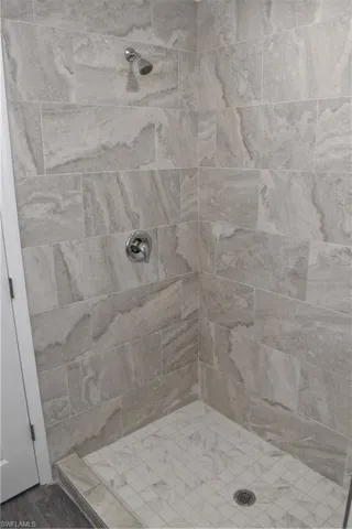 Bathroom with tiled shower and hardwood / wood-style flooring