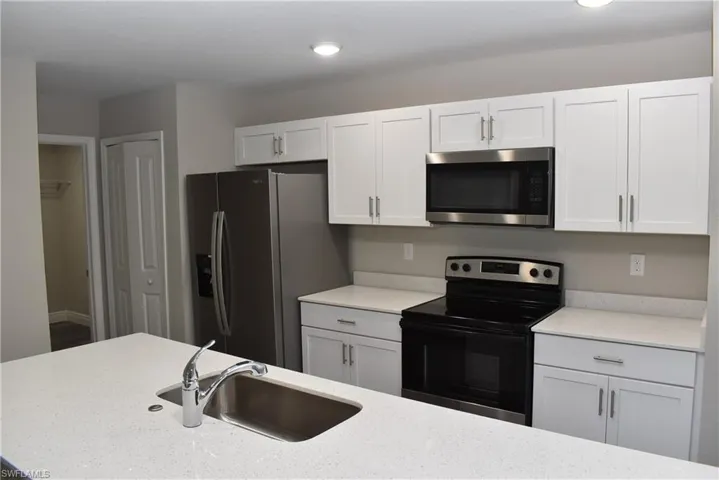 Kitchen with appliances with stainless steel finishes, white cabinetry, and sink