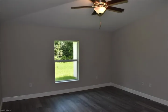 Spare room featuring a wealth of natural light, lofted ceiling, and hardwood / wood-style floors