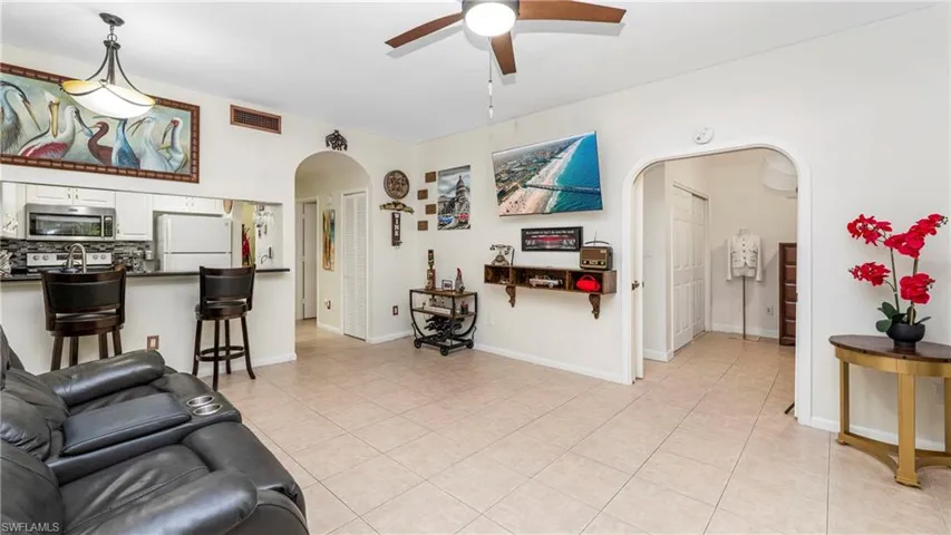 Living room featuring arched walkways, light tile patterned flooring, and a ceiling fan