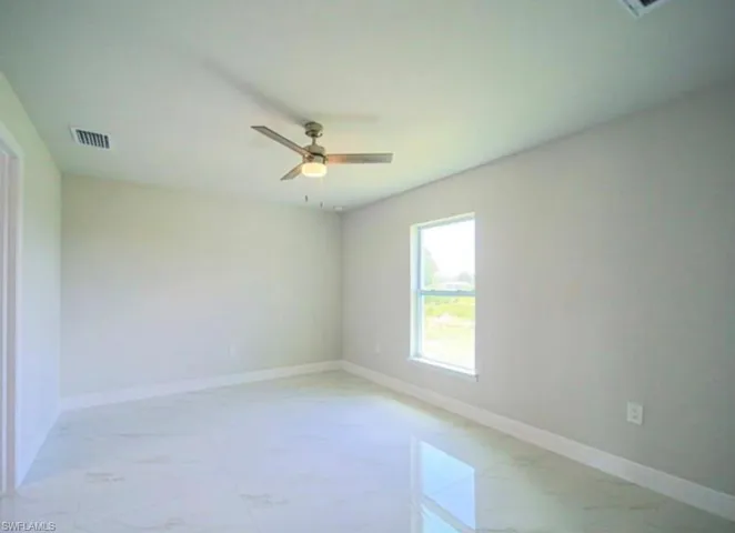 Bright interior space featuring large format tile flooring, a ceiling fan with integrated lighting, a single window, and a crisp white baseboard trim