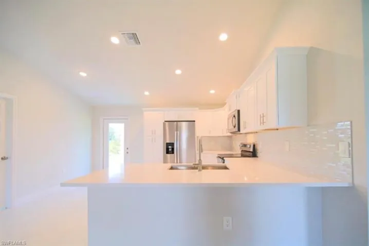 Modern kitchen featuring white cabinetry, light countertops, stainless steel appliances, a subway tile backsplash, and recessed lighting