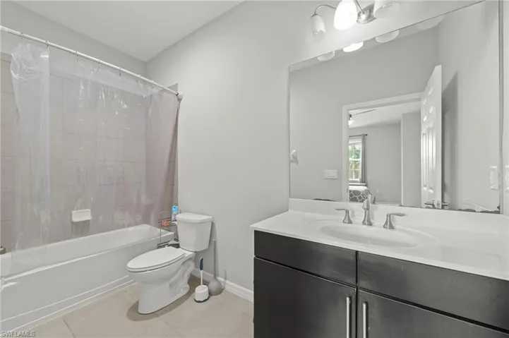 Bathroom featuring vanity, light tile patterned floors, shower / bath combination with curtain, and connected bathroom