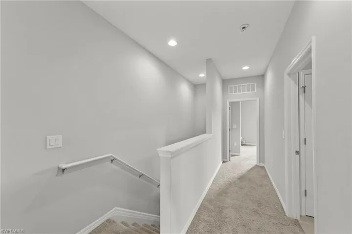 Hallway with an upstairs landing, light carpet, and recessed lighting