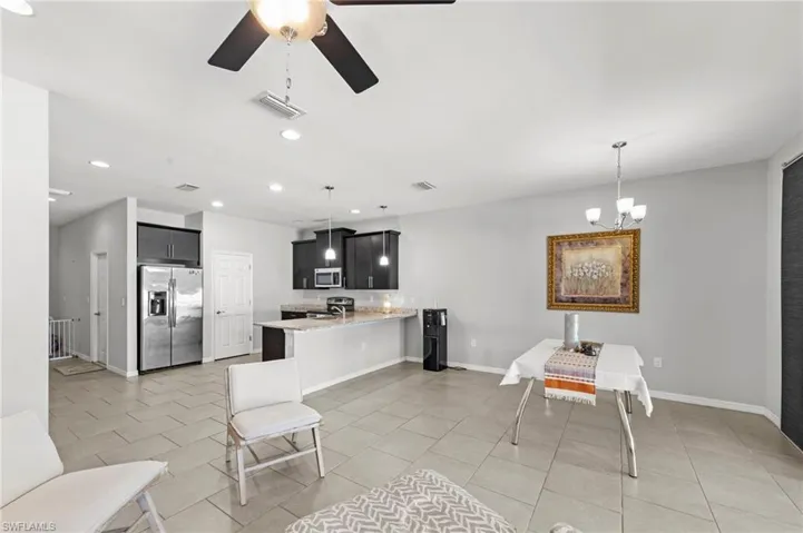 Kitchen featuring stainless steel appliances, a peninsula, a ceiling fan, dark cabinets, and light stone counters