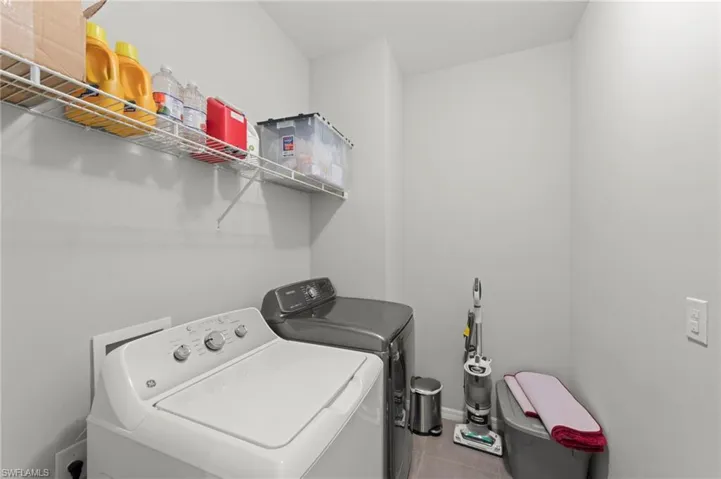Laundry area with washing machine and dryer and light tile patterned floors