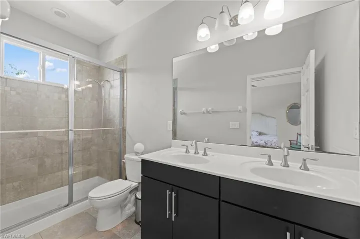 Bathroom with double vanity, ensuite bath, and a stall shower