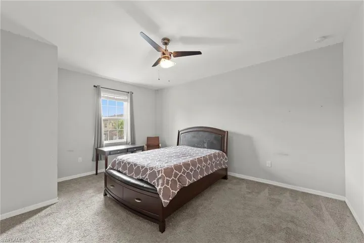 Carpeted bedroom featuring baseboards and a ceiling fan