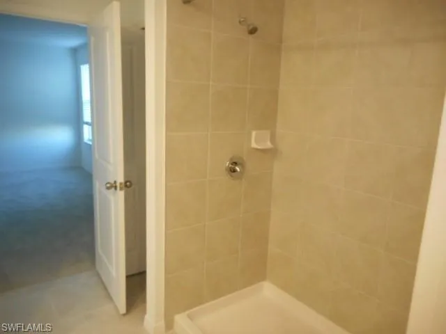 Full bathroom with a tile shower and carpet floors