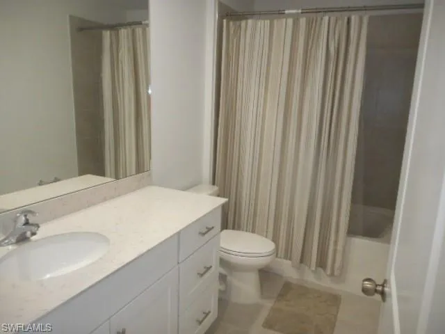 Bathroom featuring vanity, shower / bath combo with shower curtain, and light tile patterned floors