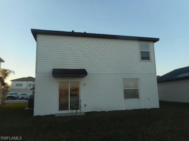 Back of house at dusk featuring a yard