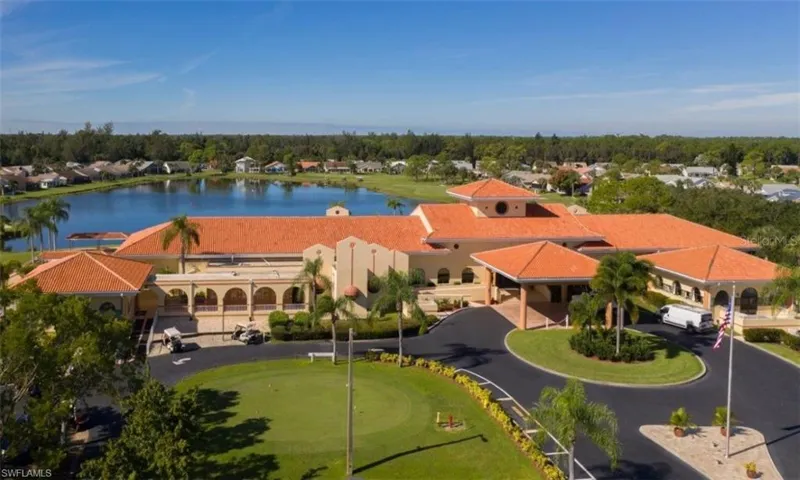 Mediterranean-inspired architecture with a tile roof, expansive circular driveway, mature palm trees, and a putting green