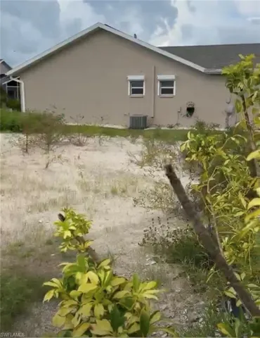 Stucco exterior with a pitched shingle roof, featuring two windows with exterior roller shutters and an outdoor air conditioning unit