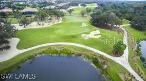 Expansive golf course setting featuring a water body, manicured greens, sand traps, and mature trees