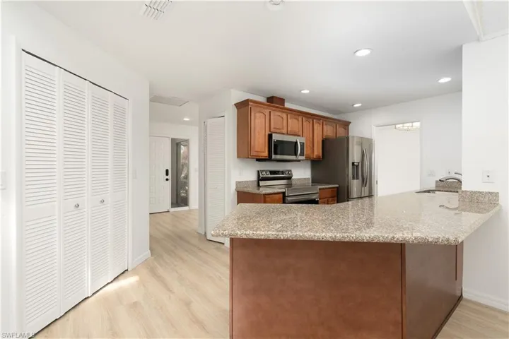 Kitchen with newer stainless steel appliances, visible vents, a sink, Pergo flooring, and breakfast bar for serving/eating. Good size pantry on the left. Freshly painted interior.