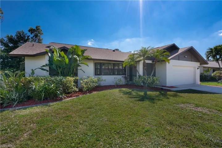 Ranch-style house with a front lawn, driveway, an attached garage, and stucco siding