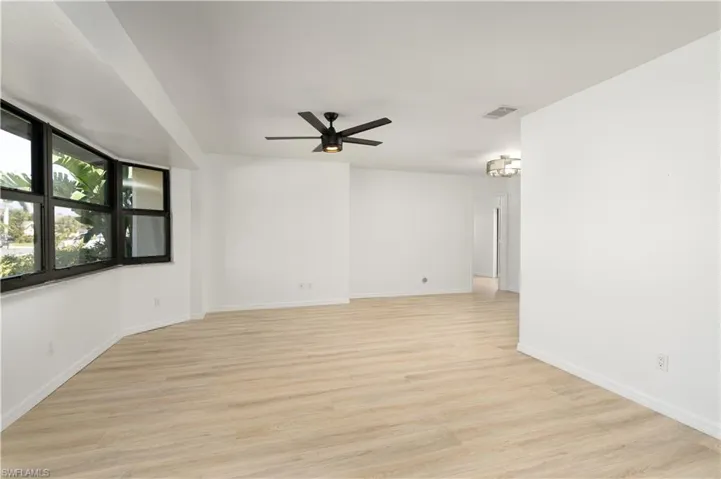Great room featuring baseboards, visible vents, ceiling fan, and Pergo flooring. Freshly painted interior.