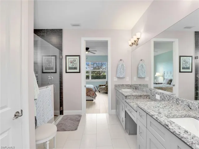 Bathroom featuring ceiling fan, vanity, tile patterned flooring, and a shower with shower door