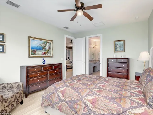 Bedroom with connected bathroom, ceiling fan, and light hardwood / wood-style flooring