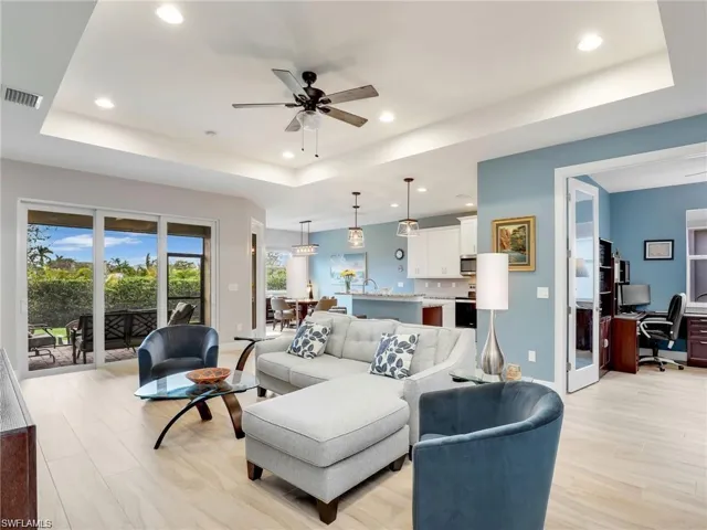 Living room with ceiling fan, light hardwood / wood-style flooring, and a tray ceiling