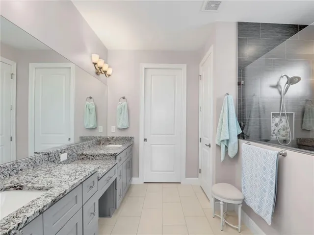 Bathroom featuring a shower, vanity, and tile patterned floors
