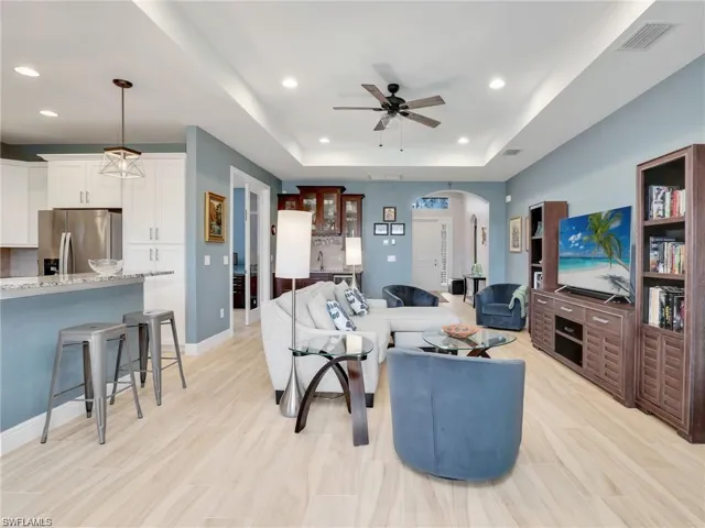 Living room featuring ceiling fan, light hardwood / wood-style flooring, and a raised ceiling