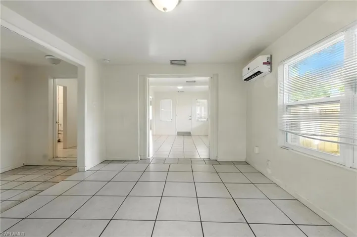 Empty room with light tile patterned flooring and an AC wall unit