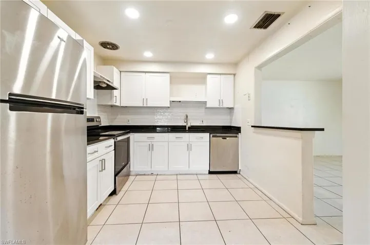 Kitchen featuring appliances with stainless steel finishes, open shelves, light tile patterned floors, white cabinets, and recessed lighting
