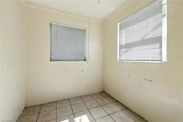 Empty room featuring ornamental molding and light tile patterned flooring