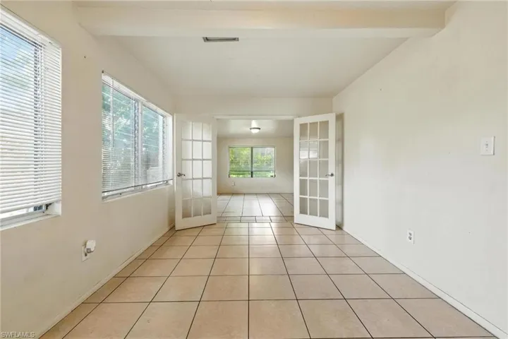 Spare room featuring french doors, light tile patterned flooring, and beamed ceiling