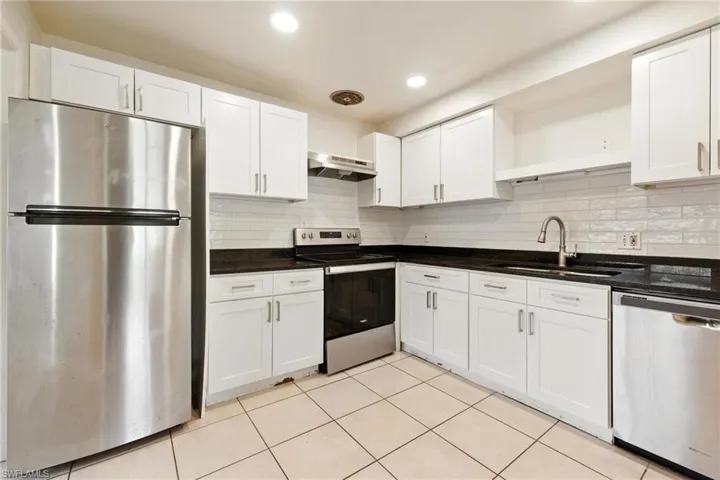 Kitchen with open shelves, appliances with stainless steel finishes, white cabinetry, light tile patterned flooring, and recessed lighting