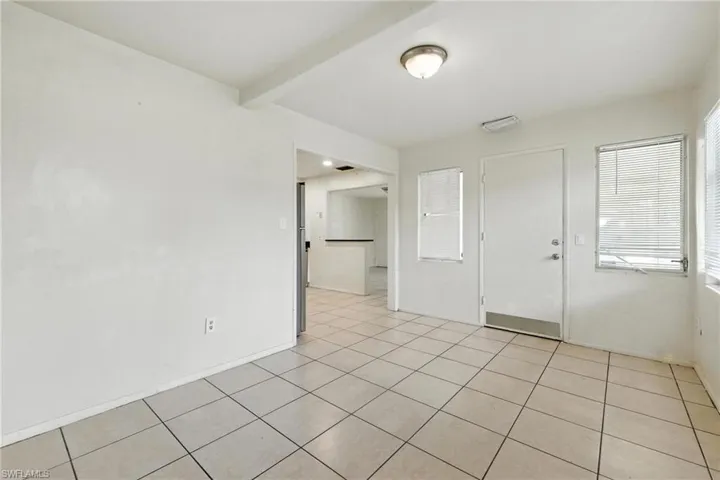Unfurnished room featuring healthy amount of natural light, light tile patterned floors, and beamed ceiling