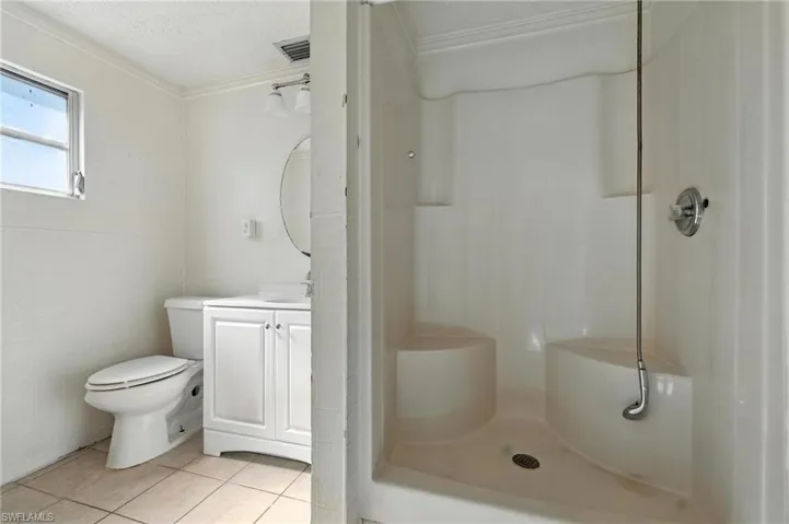 Bathroom with a stall shower, vanity, tile patterned floors, a textured ceiling, and ornamental molding