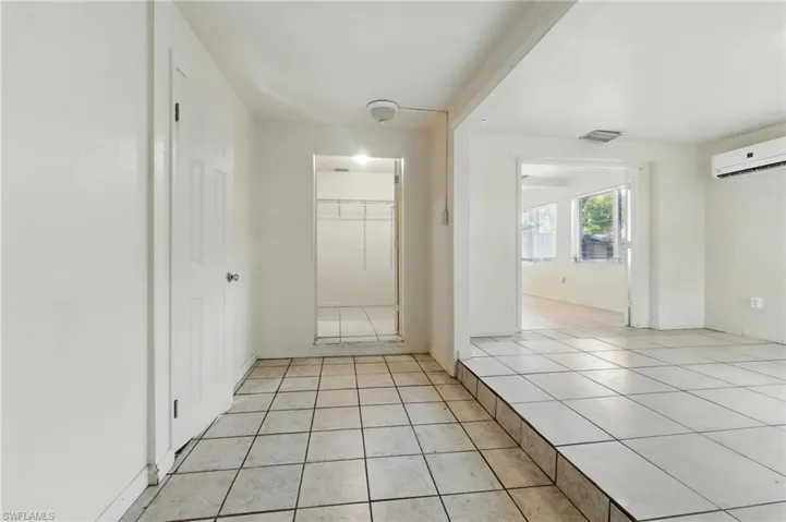 Corridor with light tile patterned flooring and a wall mounted air conditioner