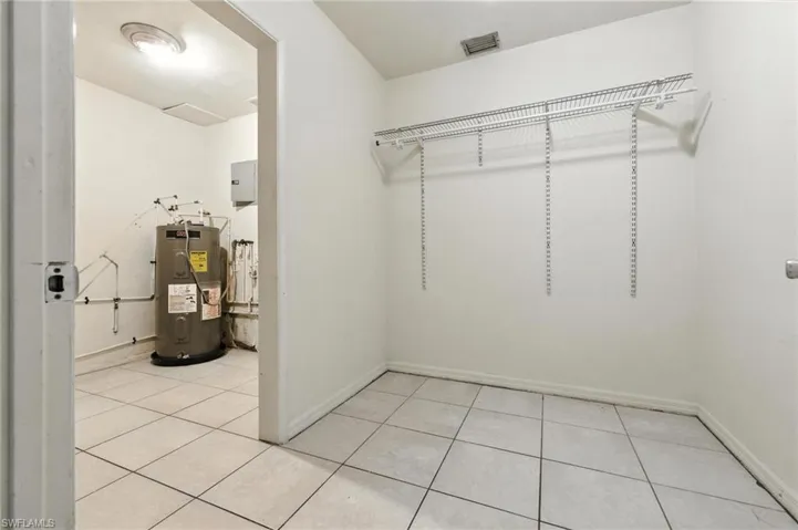 Walk in closet with water heater and light tile patterned flooring