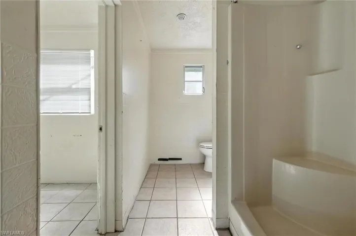 Full bathroom featuring tile patterned floors, ornamental molding, a textured ceiling, and a shower