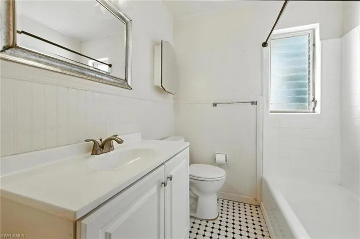 Full bath with vanity, tile patterned floors, wainscoting, and shower / washtub combination