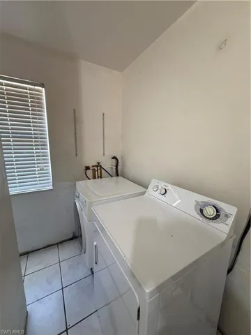 Laundry area featuring washing machine and dryer and light tile patterned floors