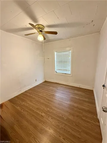 Unfurnished room with wood finished floors, ornamental molding, and ceiling fan