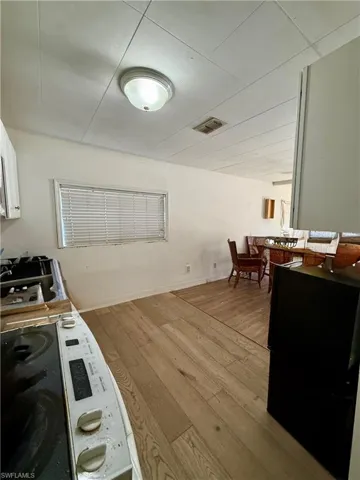 Kitchen with light wood finished floors, white electric range, and white cabinets